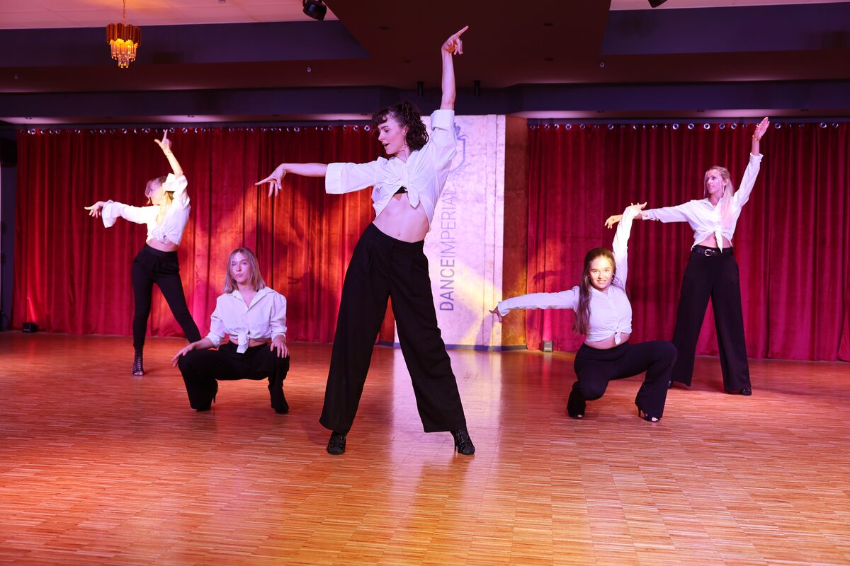 Ausdrucksstarke Choreografie in weißen Blusen und schwarzen Hosen im warmen Bühnenlicht, DANCEIMPERIAL Regensburg