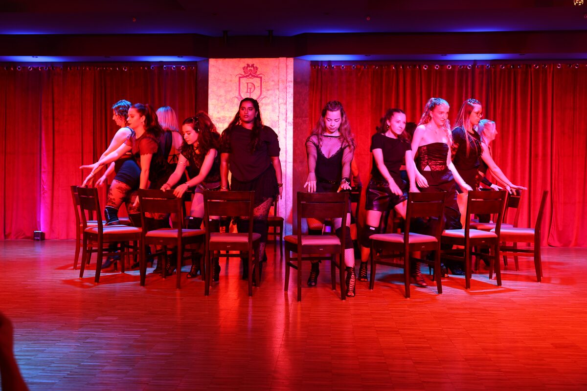 Choreografie mit Stühlen in schwarzen Outfits im roten Bühnenlicht, DANCEIMPERIAL Regensburg
