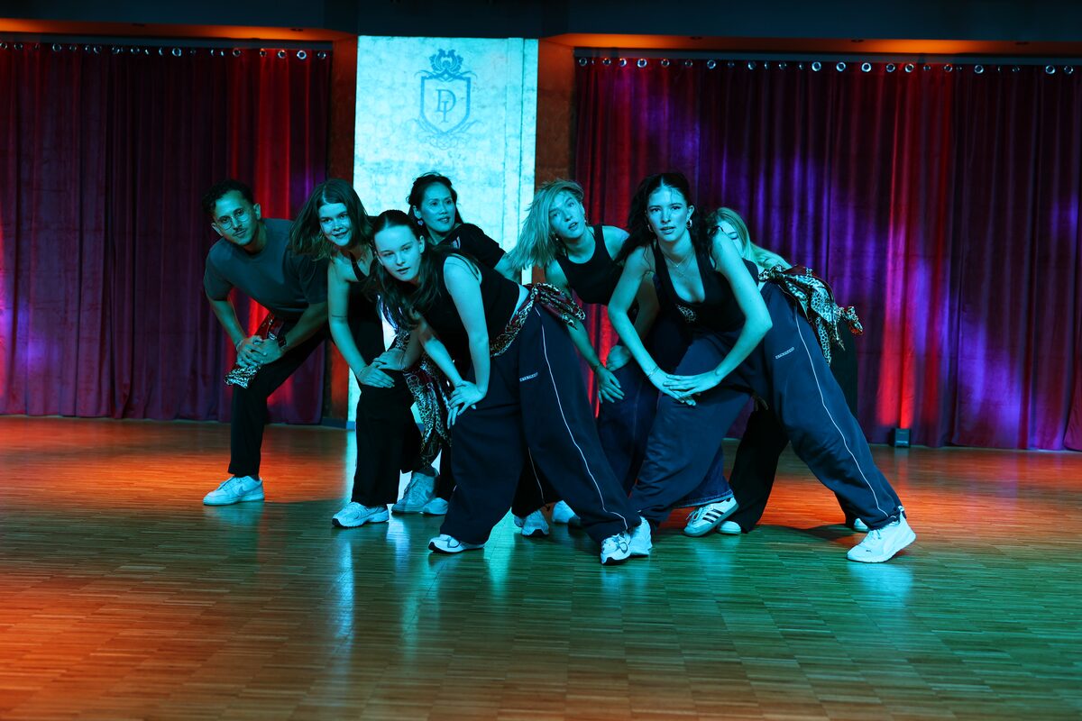 HipHop-Gruppe in dunklen Outfits in einer eng gestellten Pose im blauen Licht, DANCEIMPERIAL Regensburg