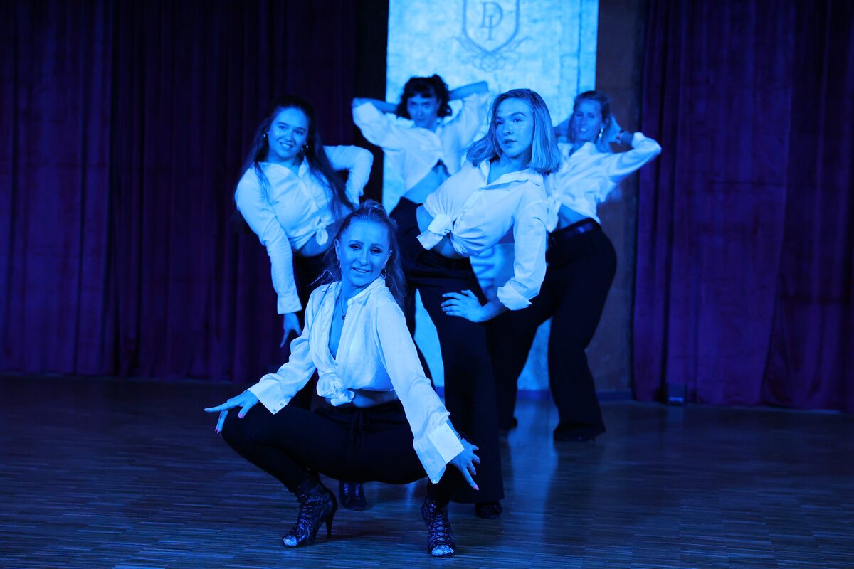 Ausdrucksstarke Pose einer Tanzgruppe im tiefblauen Bühnenlicht, DANCEIMPERIAL Regensburg